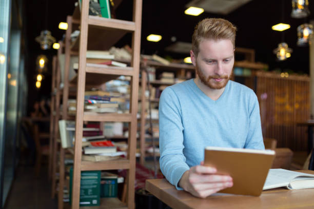 istock Young man using digital tablet in coffee shop 1077575068
