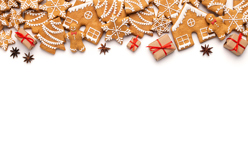 Christmas border with gingerbread cookies and aromatic spices on white background, copy space, top view