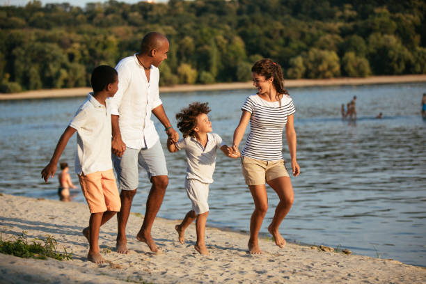 istock Beautiful family holding hands walking on the beach 1077581356