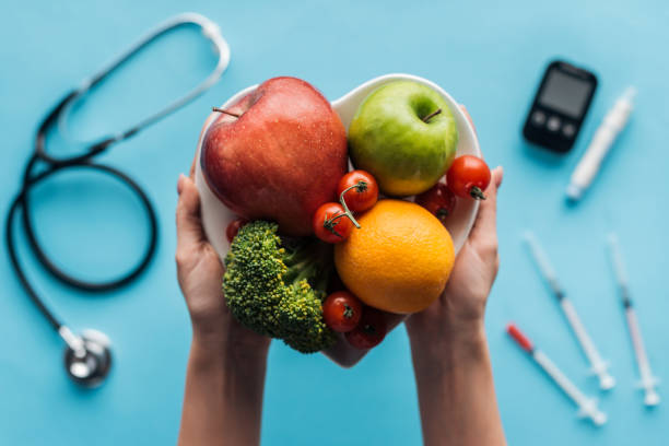 frutas y verduras en las manos femeninas con equipo médico sobre fondo azul - diabetes food fotografías e imágenes de stock