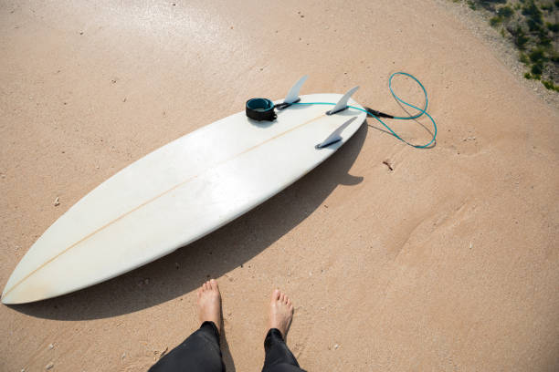 istock White Surfboard and surfer legs on beach 1077591258