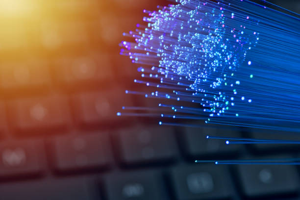 istock Fiber optics in blue, close up with keyboard background, warm lens flare 1077604718