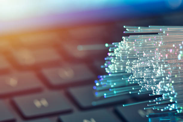istock Fiber optics in blue, close up with keyboard background, warm lens flare 1077605060