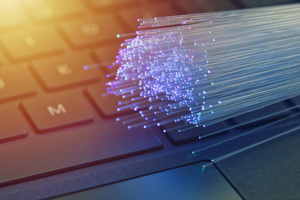 istock Fiber optics in blue, close up with keyboard background, warm lens flare 1077605188