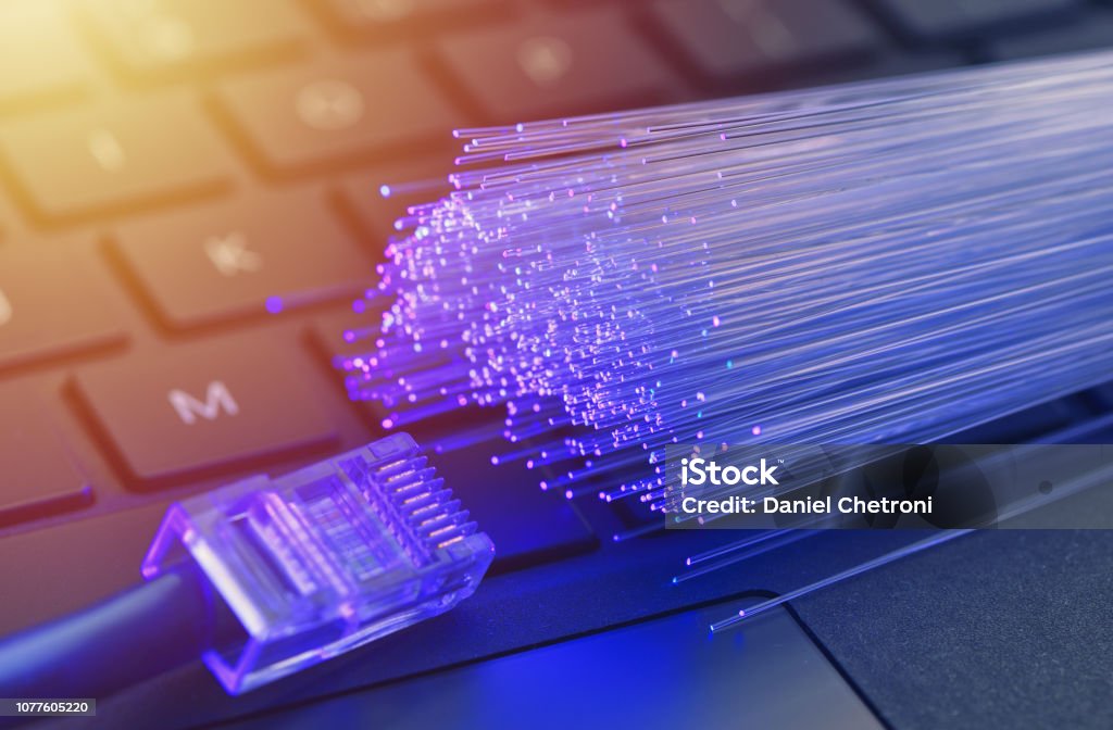 Fiber optics in blue, close up with ethernet and keyboard background, warm lens flare Fiber Optic Stock Photo