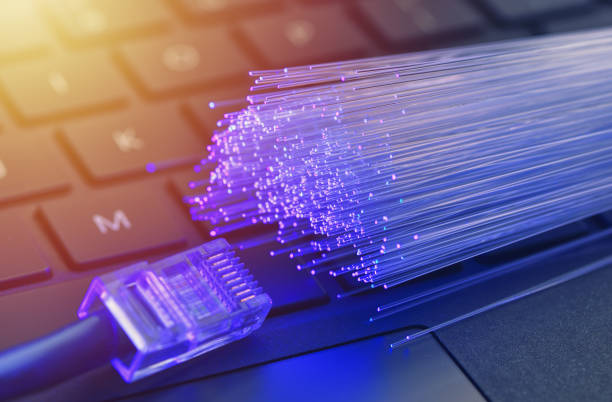 Fiber optics in blue, close up with ethernet and keyboard background, warm lens flare stock photo