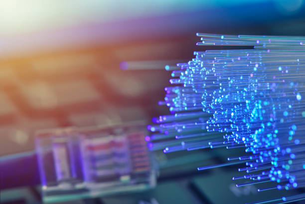 istock Fiber optics in blue, close up with ethernet and keyboard background, warm lens flare 1077605376