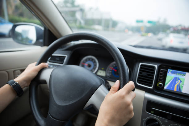 istock Hands holding steering wheel while driving car on city road 1077606940