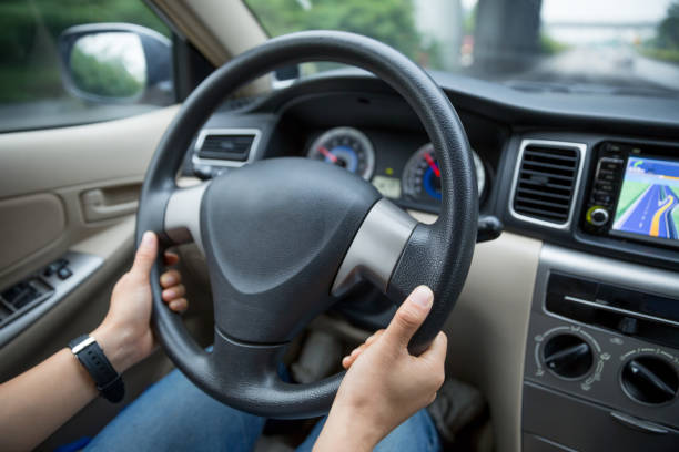 istock Hands holding steering wheel while driving car on city road 1077607166