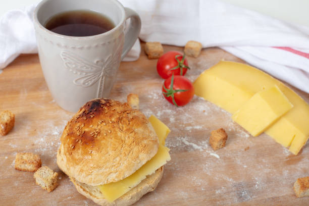 Freshly baked homemade sandwich with beverage on wooden cutting board with   cherry tomatoes , traditional cheddar and flour  High angle view with copy space