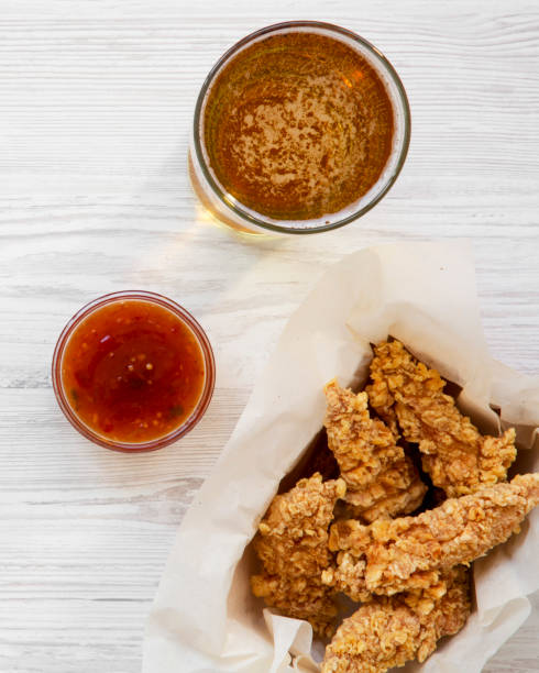 istock Chicken strips with sauce and cold beer on a white wooden background, top view. Overhead, flat lay. Close-up. 1077615440