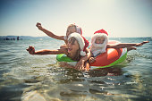 Kids playing in sea on swim ring during summer Christmas