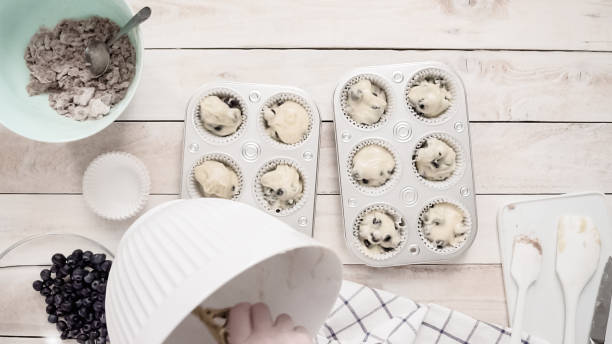 istock Scooping blueberry muffin batter into metal muffin pan. 1077622448
