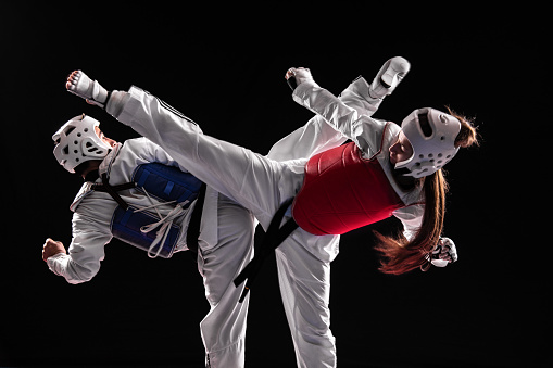 Young man and woman in taekwondo combat. Fight of two black belts