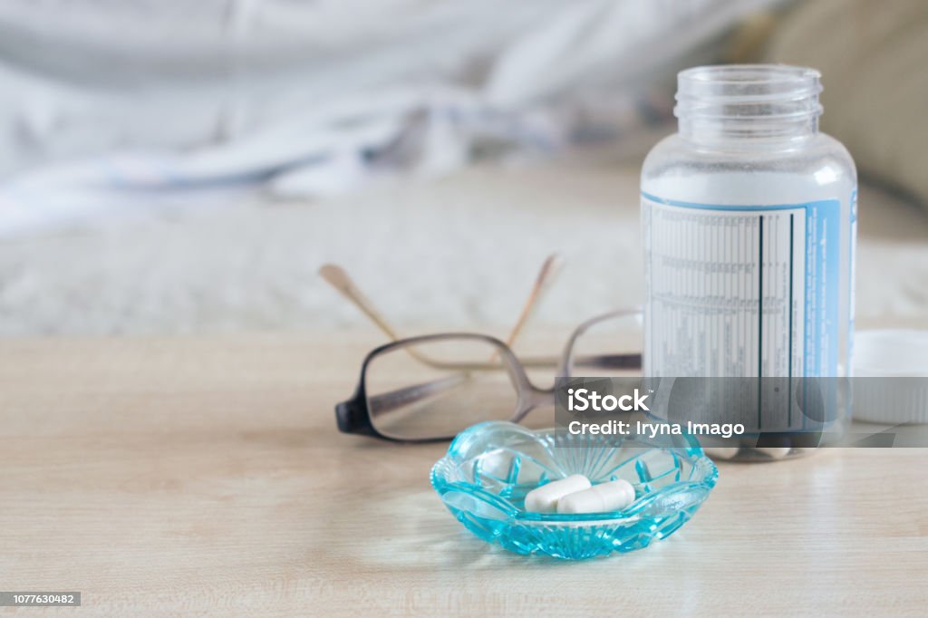 Thuốc ngủ, thuốc thôi miên, thuốc an thần, melatonin. Viên nang trong bát thủy tinh với kính và chai thuốc trên bàn gần giường - Trả phí Bản quyền Một lần Buổi tối - Thời gian trong ngày Bức ảnh sẵn có Thuốc ngủ, thuốc thôi miên, thuốc an thần, melatonin. Viên nang trong bát thủy tinh với kính và chai thuốc trên bàn gần giường - Trả phí Bản quyền Một lần Buổi tối - Thời gian trong ngày Bức ảnh sẵn có