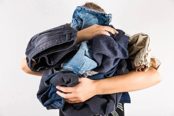 Photo of Woman holding huge pile of clothes - laundry concept