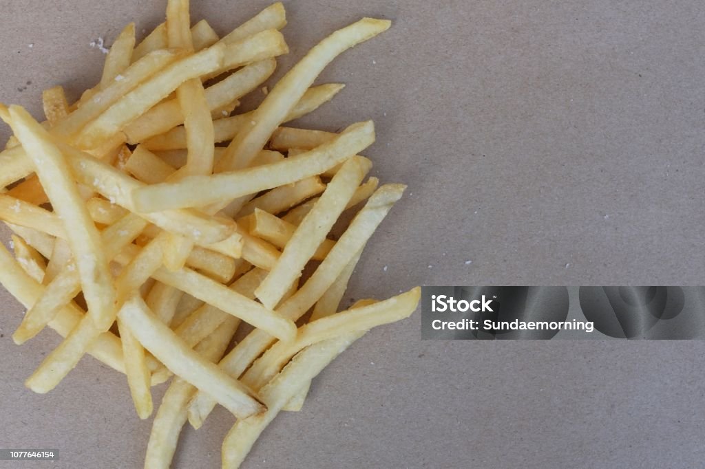 Unhealthy junk food, group of cheesy french fries on brown paper with blank space, copy space, fast food concept French Fries Stock Photo