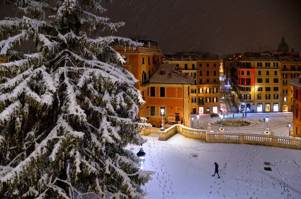 Night snowfall on empty Spanish square and steps in Rome with old buildings and architecture in background, Italy. Piazza di Spagna