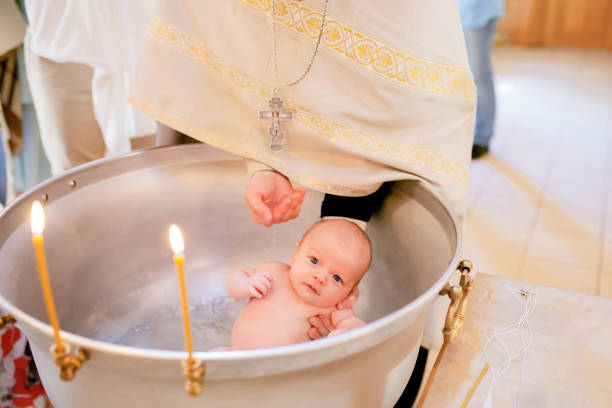 Baptism of newborn child in the Orthodox Church. Baby christening. Baptism of newborn child in the Russian Orthodox Church. Baby christening. Baby in font with hands of priest. baptismal font stock pictures, royalty-free photos & images