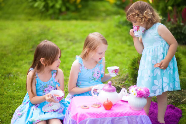 tres hermanas jugando partido de té al aire libre - tea party little girls teapot child fotografías e imágenes de stock