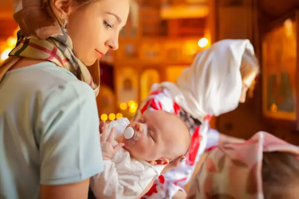 Baptism of a newborn child. Child in the arms of mother. Religion, church.