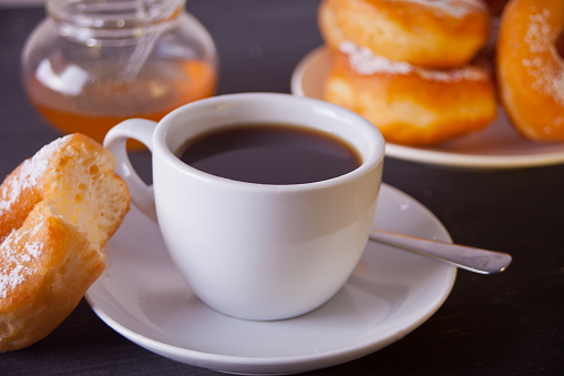 Fresh donuts with cup of coffee on the wooden dark table
