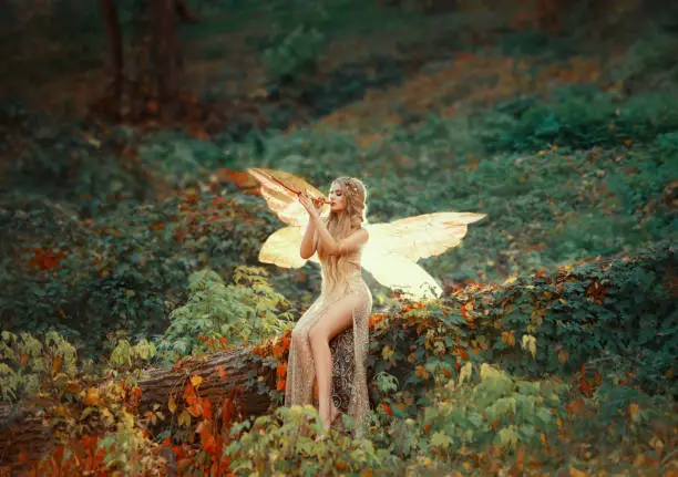 lovely girl druid with blond long hair, sits on a fallen tree, dressed in a gorgeous beige dress with open sexy slim legs, transforming into a light forest butterfly, flashing on a wooden pipe alone.