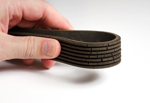 The old worn out rubber alternator belt in men's hand. The concept of car maintenance