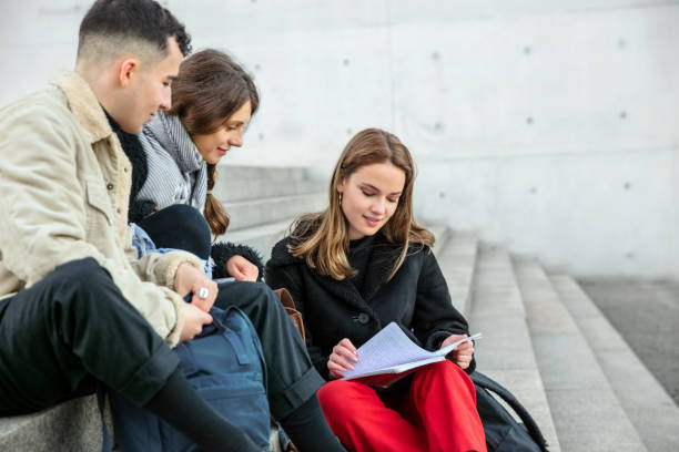 istock Group of students sitting on step with a book 1077670470