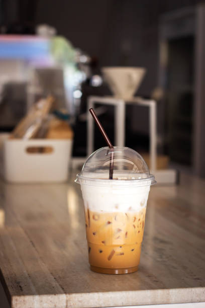Ice cappuccino in plastic cup on counter bar of cafe. Refreshment beverage.