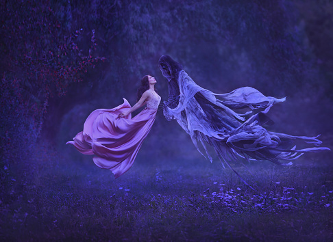 The mysterious witch is dancing with a demon, dark forces, in the air. Freedom, to escape from slavery.. Taking away the soul. A dress waving in the wind during the flight. Art photo of levitation.