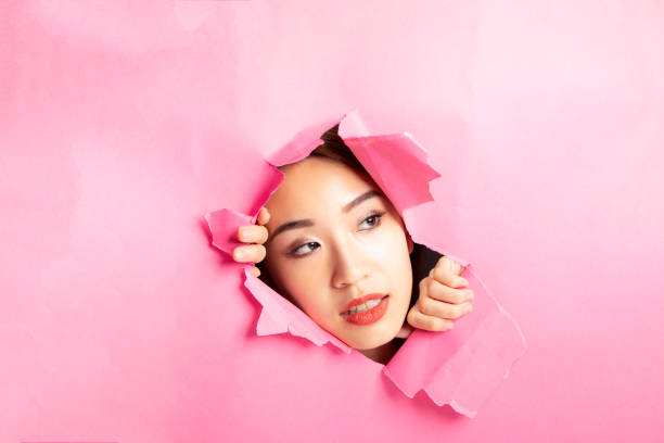 istock Asian woman expression through torn paper hole 1077674286