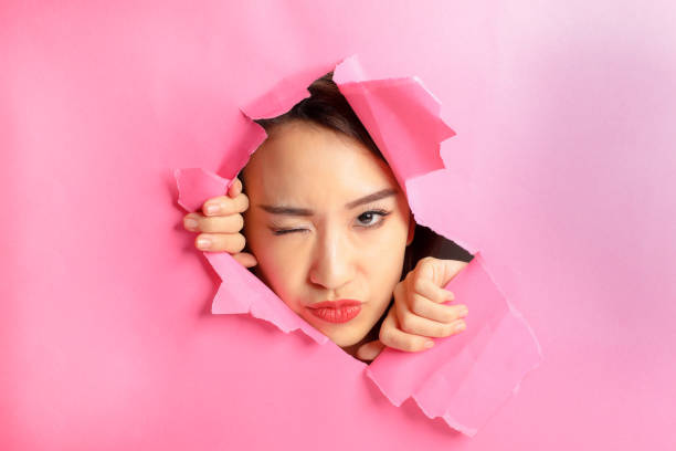 istock Asian woman expression through torn paper hole 1077674586