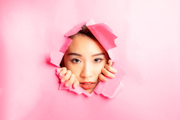 istock Asian woman expression through torn paper hole 1077681936
