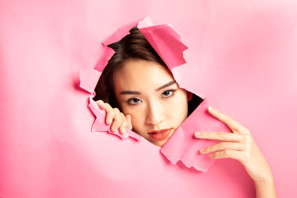 istock Asian woman expression through torn paper hole 1077682128