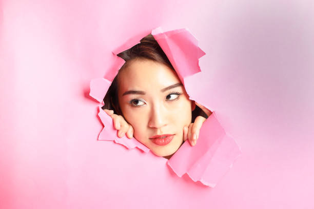 istock Asian woman expression through torn paper hole 1077682292