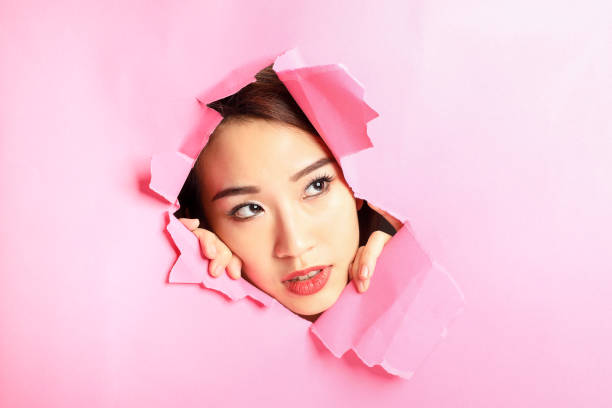 istock Asian woman expression through torn paper hole 1077682294