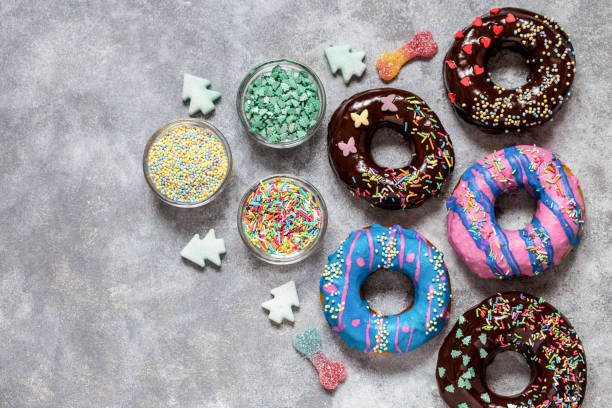 homemade doughnuts with colored frosting and sprinkles on a gray background