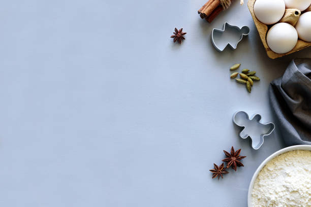 istock Cooking Christmas cookies. Ingredients for gingerbread dough: flour, eggs, sugar, cocoa, cinnamon sticks, anise stars and cookie cutters on gray wooden background. Flat lay. Top view. Copy space 1077685410