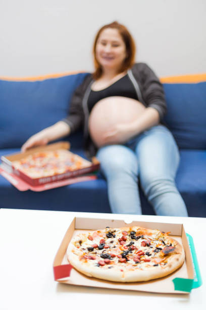 istock Pregnant woman eating pizza 1077687352