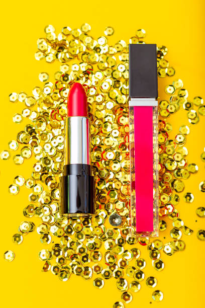 istock Red lipstick and crimson lip gloss on a yellow background. Vertical 1077687416