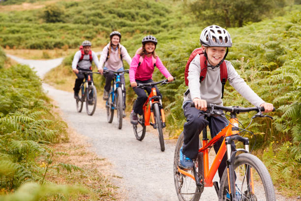 ragazzo pre-adolescente in mountain bike con la sorella e i genitori durante un campeggio in famiglia, da vicino - family with two children father clothing smiling foto e immagini stock