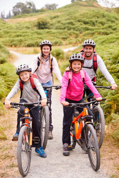 родители и дети, сидящие на горных велосипедах в промеханом переулке во время семейного похода, по всей длине - bicycle lane стоковые фото и изображения