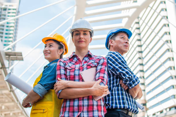 три инженера-индустрии носят защитный шлем, стоящий со скрещенными руками на здании снаружи. инженерные инструменты и концепция строитель� - contracting construction built structure concrete стоковые фото и изображения