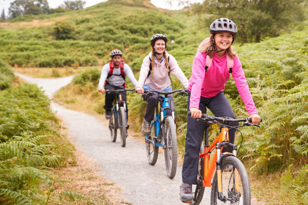 bicicleta de montaña niña preadolescente del montar a caballo con sus padres durante un viaje de camping familiar, cerca - helmet bicycle little girls child fotografías e imágenes de stock