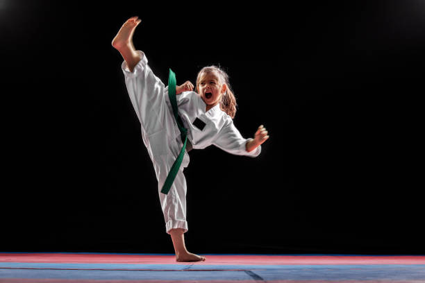 Girl practicing martial arts Young girl practicing taekwondo high kick in the air. Taekwondo is one of the most popular martial arts. She is working in gym with dark background taekwondo stock pictures, royalty-free photos & images