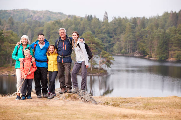 istock Multi generation family stand embracing by a lake, smiling to camera, front view, Lake District, UK 1077694030