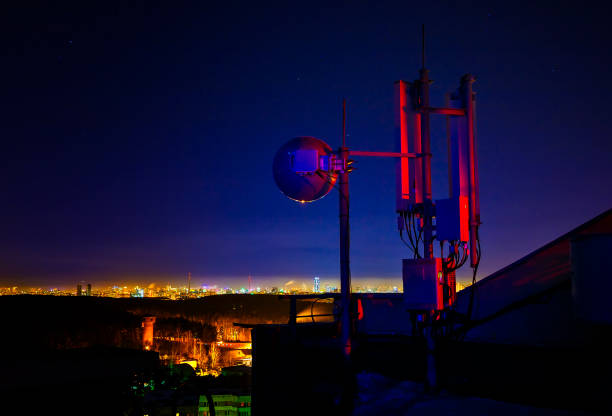 Telecommunications tower, antenna and satellite dish and city at night as background stock photo
