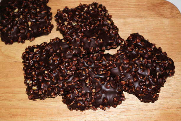 istock Five chocolate square cookies with nuts on a wooden board 1077695798