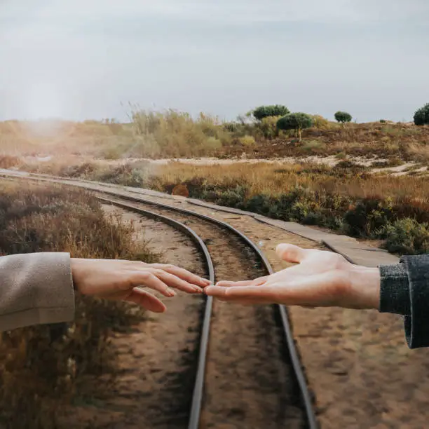 moody - hands of a couple at railroad tracks. travel together in the future
